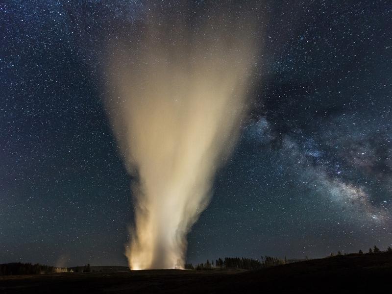 Old Faithful erupts at night beneath the clear constellation of The Milky Way. Photograph by Neil Herbert/NPS 