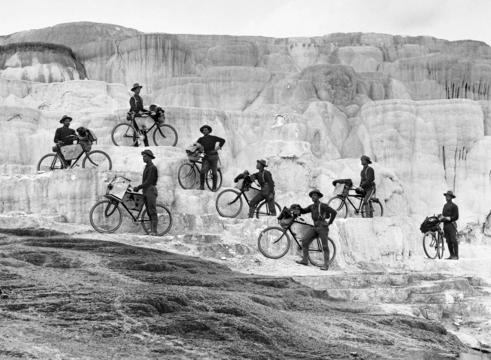 Members of a cavalry unit known as the Buffalo Soldiers ride their frontier bicycles onto the fragile travertine at Minerva Terrace in Yellowstone.