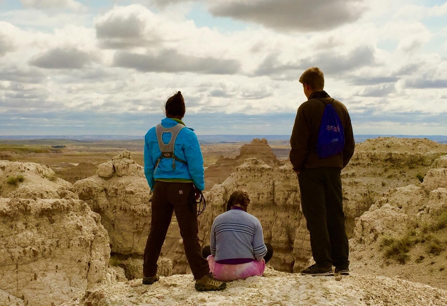 How do young people not only find their voice but seize it in intergenerational discussions about the future of the American West? Here, students from Whtiman College gaze into the maw of Badlands National Park's South Unit located inside the Pine Ridge Indian Reservation in South Dakota.  They are not far from the 100th Meridian, the place where John Wesley Powell said the West, topographically, begins. Photo by Todd Wilkinson