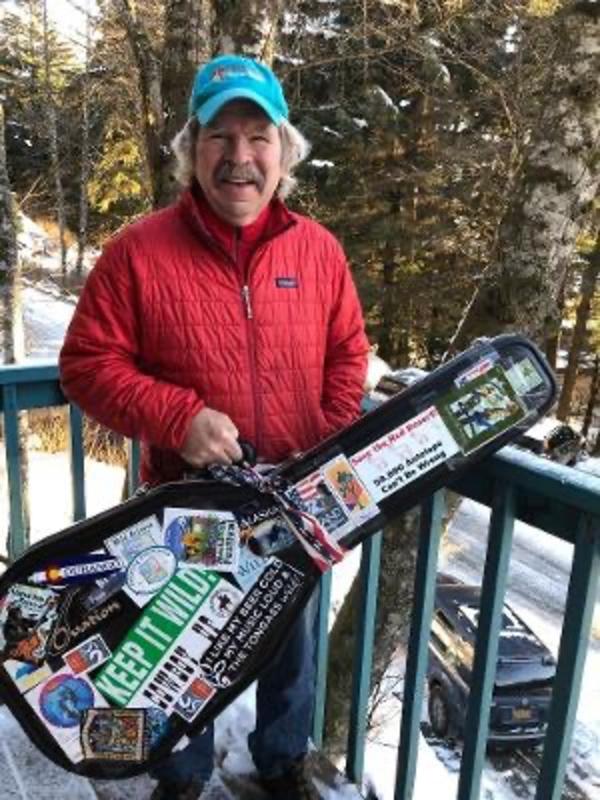 Koehler with a guitar case covered with many of his conservation bumper stickers.