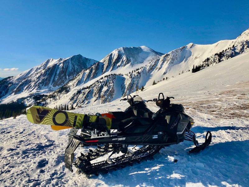 A pair of snowmobiles that carried snowboarders into the backcountry