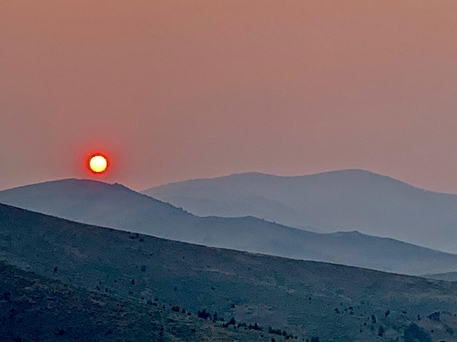 While smokey sunsets like this one falling below the Tobacco Roots west of Bozeman possess a strange beauty, the unhealthy air speaks to how ubiquitous the wildfire menace is even for people who do not live in the WUI. Photo by Todd Wilkinson