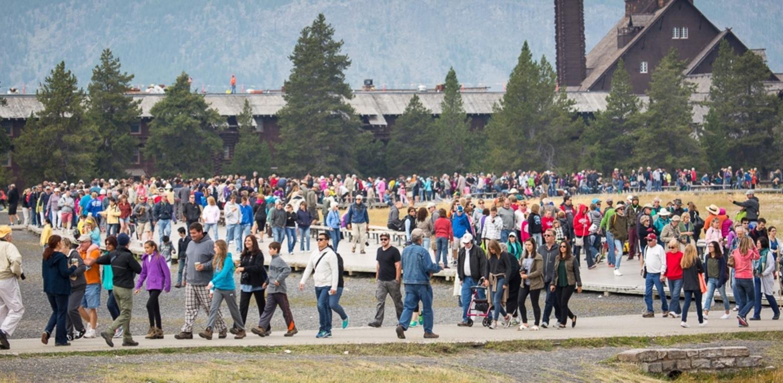 A summer eruption of visitors in Yellowstone encircles the rim of Old Faithful, waiting for the world's most famous geyser  to send its hot water plume skyward.  Photo courtesy National Park Service/Neal Herbert.