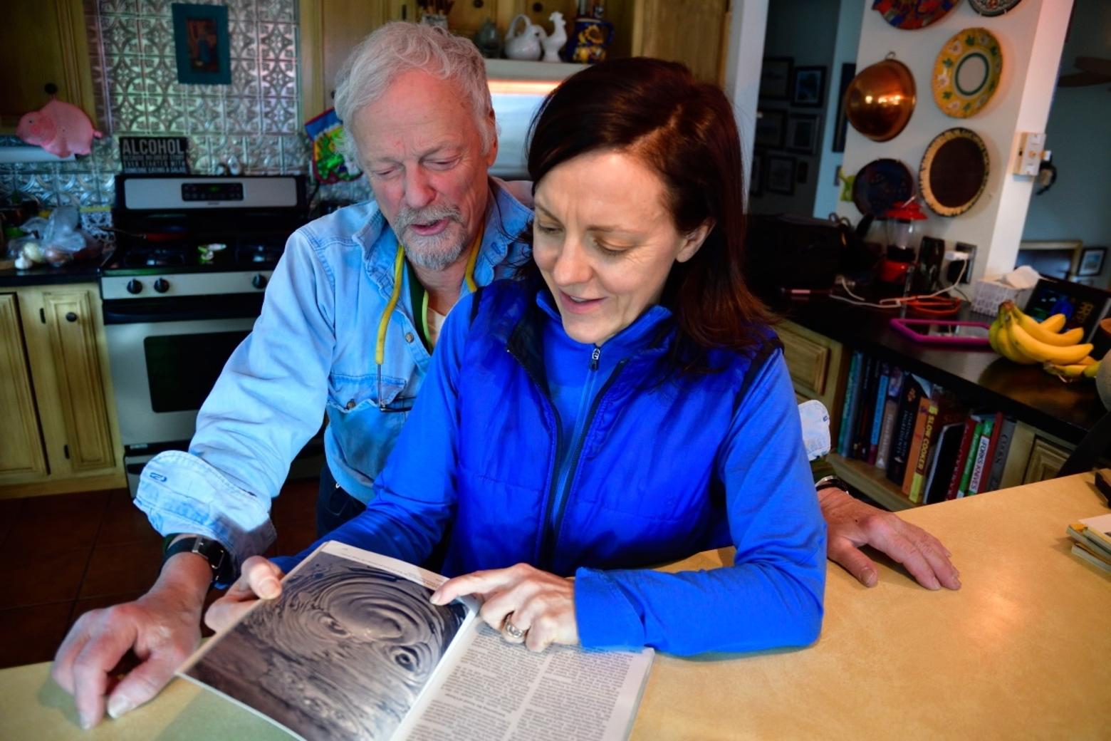 Fuller and his now-grown daughter, Emma, flip through the pages of National Geographic's 1978 issue in which Fuller chronicled his family's life in Yellowstone and his adventures as winterkeeper.  Photo by Joe Sawyer