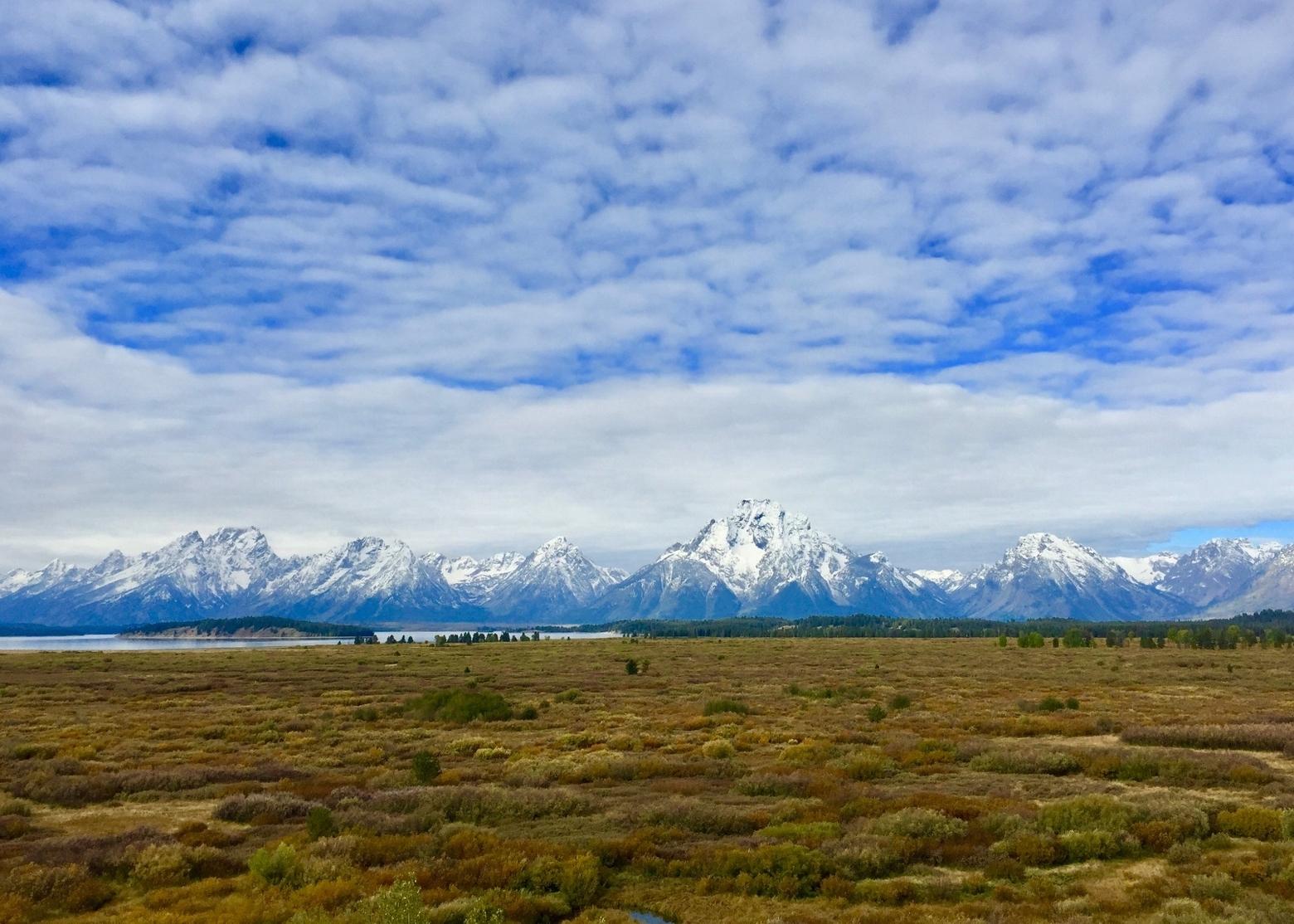 The Tetons from east of Jackson Lake.  Imagine if these flats, today teeming with wildlife and serving a visual sightline to the mountains, were instead covered with a residential subdivision or commercial development all the way almost to the water's edge. While today these lands are treasured as a vital part of Grand Teton National Park's character, some fought against landscape protection.  Photo by Todd Wilkinson