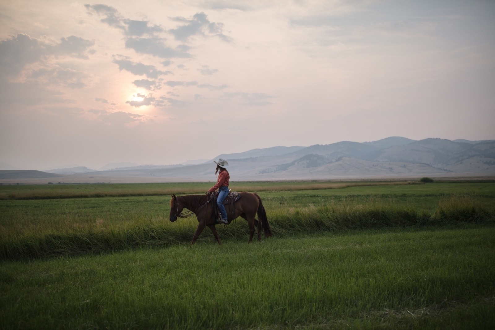 Irene Johnson rides her horse, Perky, on her home ranch under a smokey Montana sky. Photo by Louise Johns