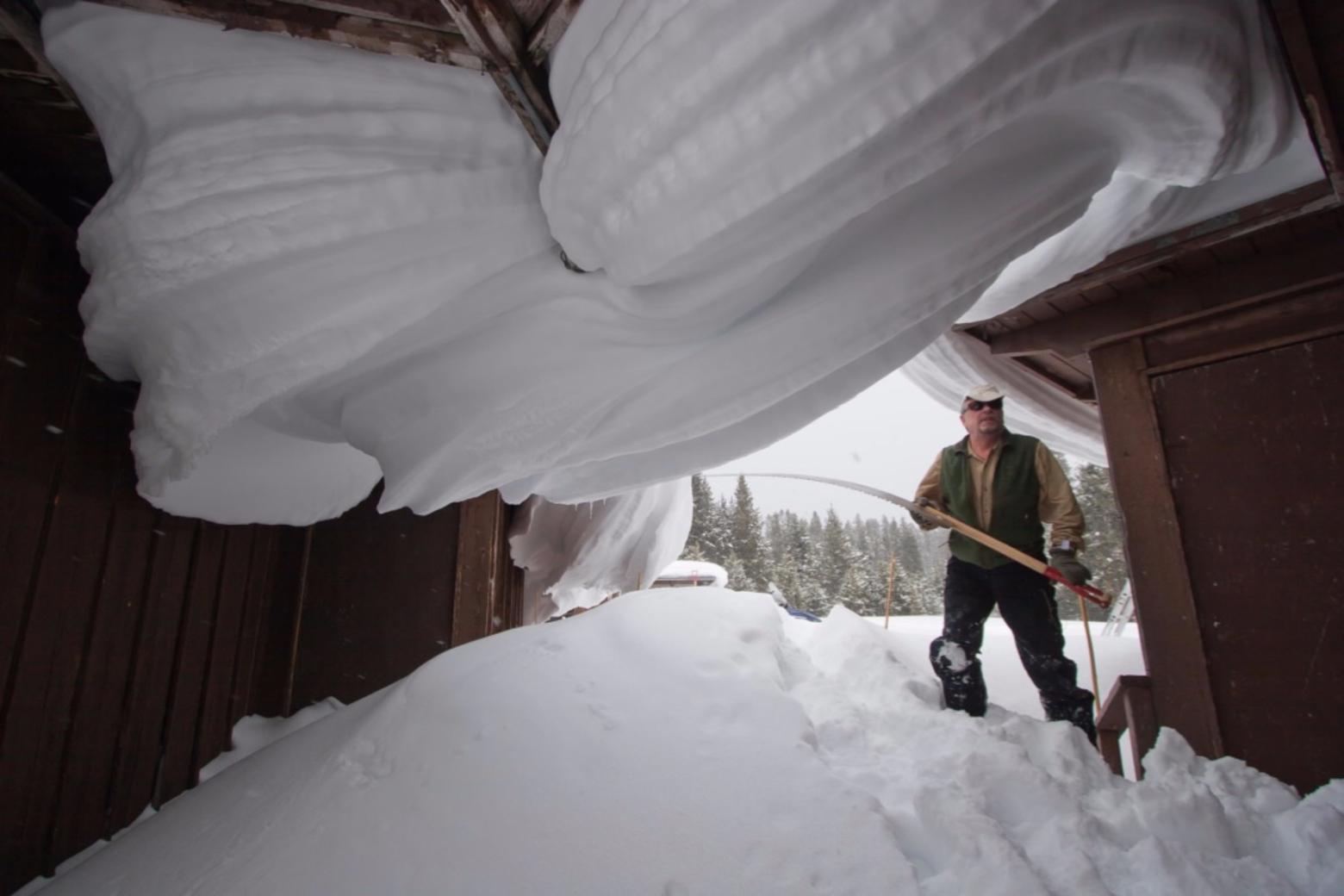 When Fuller last wrote for Mountain Journal he was putting another winter to bed.  Here, with saw in hand, he works a heavy snowfall to prevent a roof in Yellowstone from collapsing.