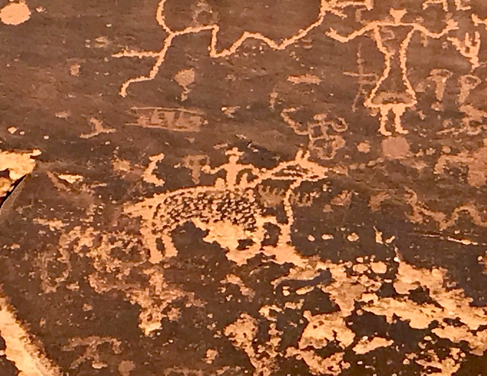 Re-writing the history of who was in the West first?  A cowboy image is carved into a rock wall, over the top of ancient indigenous petroglyphs near Bluff, Utah. Photo by Betsy Gaines Quammen