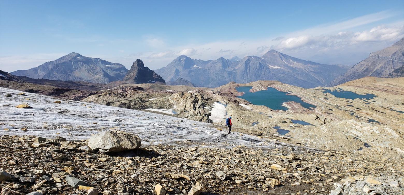 Here, a researcher stands in the terminal, lowest-elevation segment of Sperry Glacier in Glacier National Park, Montana.  Sperry is one of five benchmark glaciers being closely studied by the USGS to track the retreat of their size and mass. This photograph was taken in September 2020 by researcher Dr. Caitlyn Florentine, who is based out of the USGS's Northern Rocky Mountain Science Center in Bozeman. By visiting the following link, you can see a simulated map of Sperry's retreat in size since 1960.  Go to https:www2.usgs.gov/landresources/lcs/glacierstudies/sperry.asp