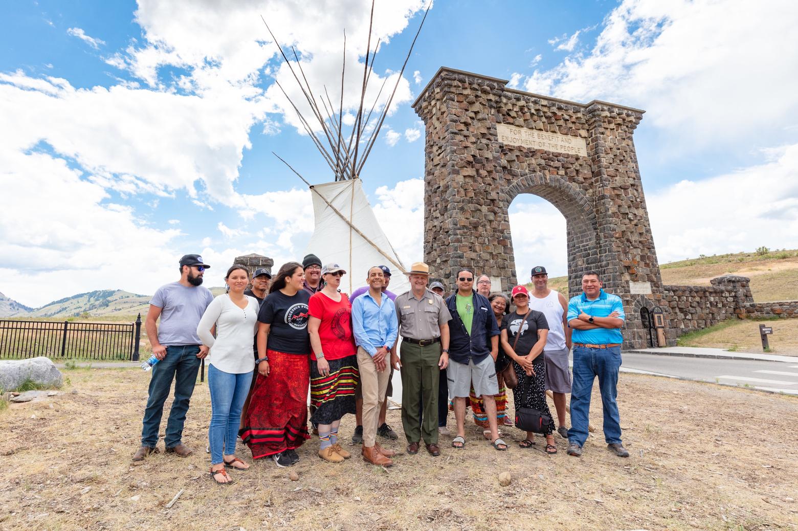 Some of the tribal representatives, artists and Park Service leaders who gathered for the tipi installation at Yellowstone's front entrance. The event was marked by an honoring song from Shane Doyle pictured in blue shirt, center and Sholly to his right. Photo courtesy Jacob W. Frank/NPS