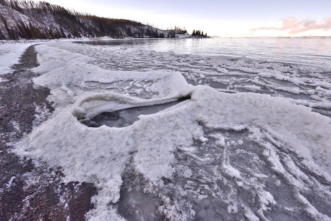In the weeks before Yellowstone Lake freezes, the surface of the water becomes super-cooled so multitudes of small floating ice crystals (frazil ice) accumulate in the water on the lee shore. Wind-driven waves splash when they crash on the beach., quickly building up cones of frazil ice.