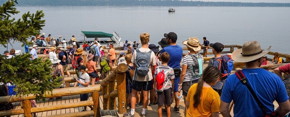 Visitors wait to catch a boat ride across Jenny Lake in Grand Teton National Park. What's not in view is a huge parking lot complex, overflowing in summer, just off the east shore of Jenny. Grand Teton, which recorded a whopping 3.8 million visits in 2021, also has the busiest commercial airport in the state inside its borders. Huge numbers of visitors have also brought an inundation of people to campgrounds and trails on the nearby Bridger-Teton National Forest. What is the answer?  Photo courtesy J. Bonney/NPS
