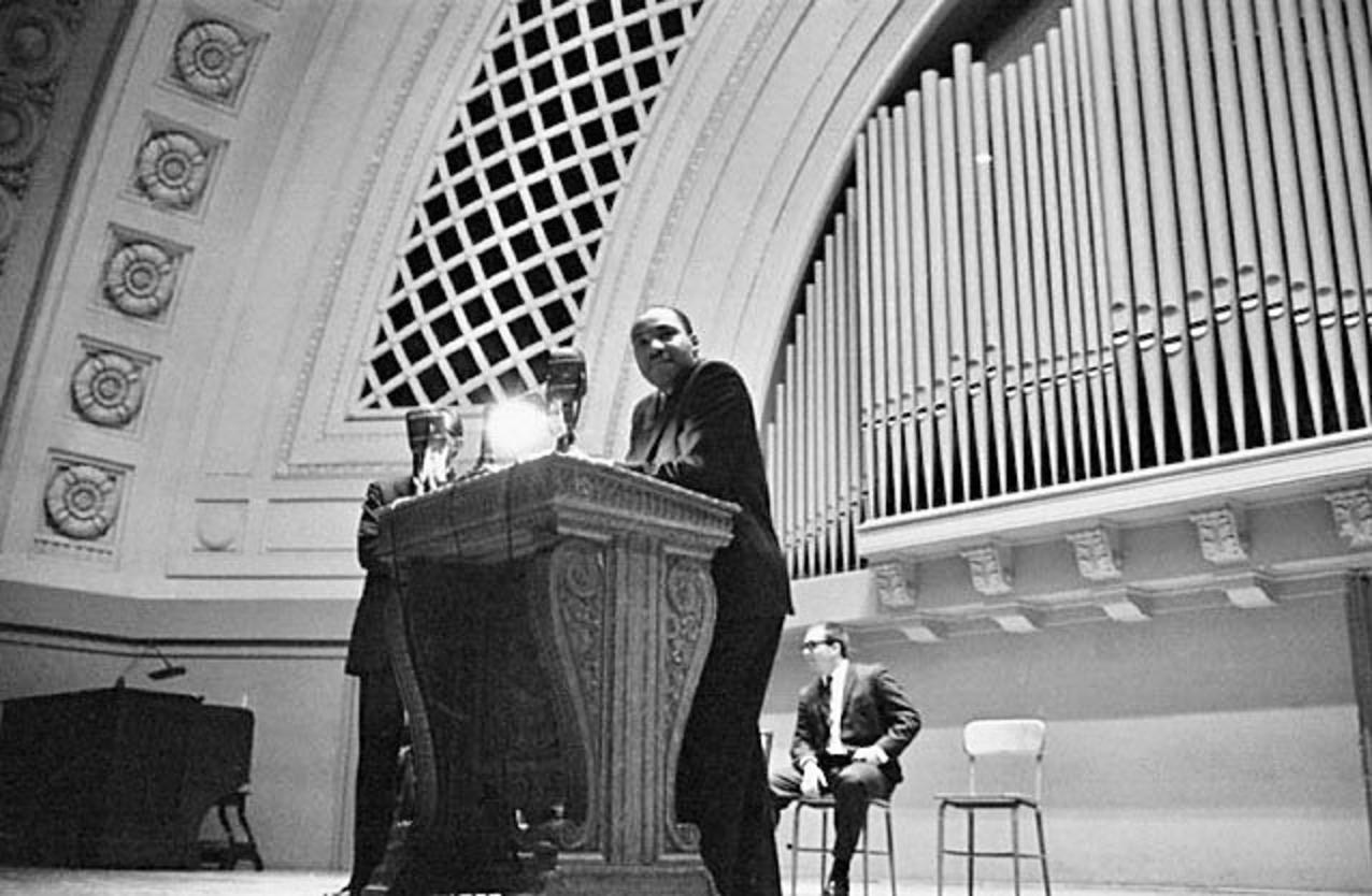 As Dr. Martin Luther King Jr. gives an oration before a full auditorium at the University of Michigan in 1962, young Douglas Peacock, who invited King to campus, sits behind him bespectacled and dressed sharply in a suit. Three years later, Peacock's draft number came up and he was sent to Vietnam where he became a Green Beret medic; six years after the reverend's visit, just days after he returned home, King was assassinated in Memphis. Why does Peacock relate to grizzly bears and want to defend them from traumatic treatment by people?  Because he knows what the human species is capable of and wants to preserve these creatures who live in the same wild places that gave him solace after the war. Photo courtesy Doug Peacock