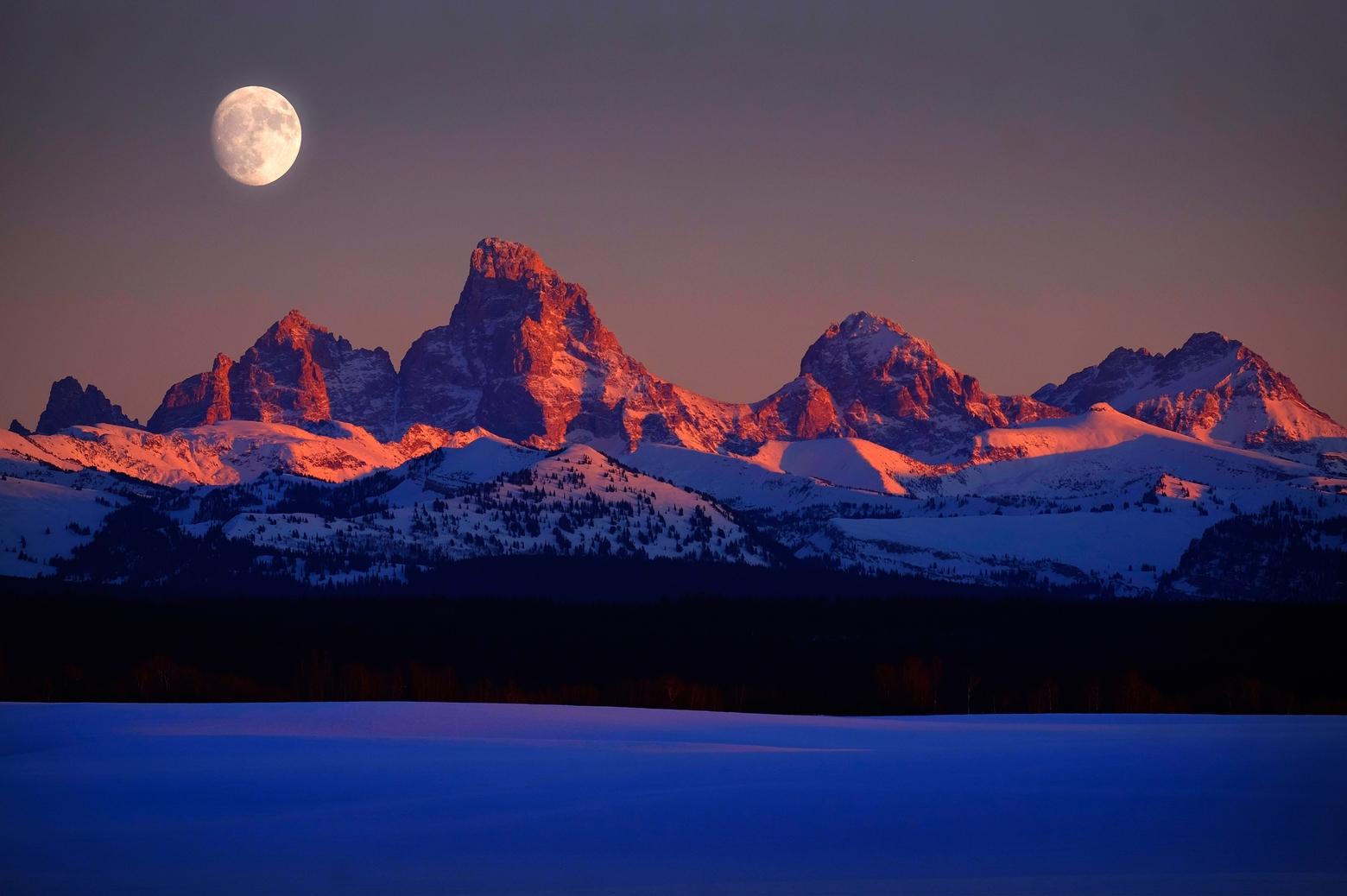 Known for its pastoral setting and sense of wildness that extends from Teton Valley, Idaho northward to Yellowstone and beyond, the west side of the Tetons have a different vibe and sense of community from what's found on the other side of the mountains in Jackson Hole.  Here, amid moonrise, sunset casts the summits in alpenglow. Photo by Lane V. Erickson/Shutterstock ID: 1288379848
