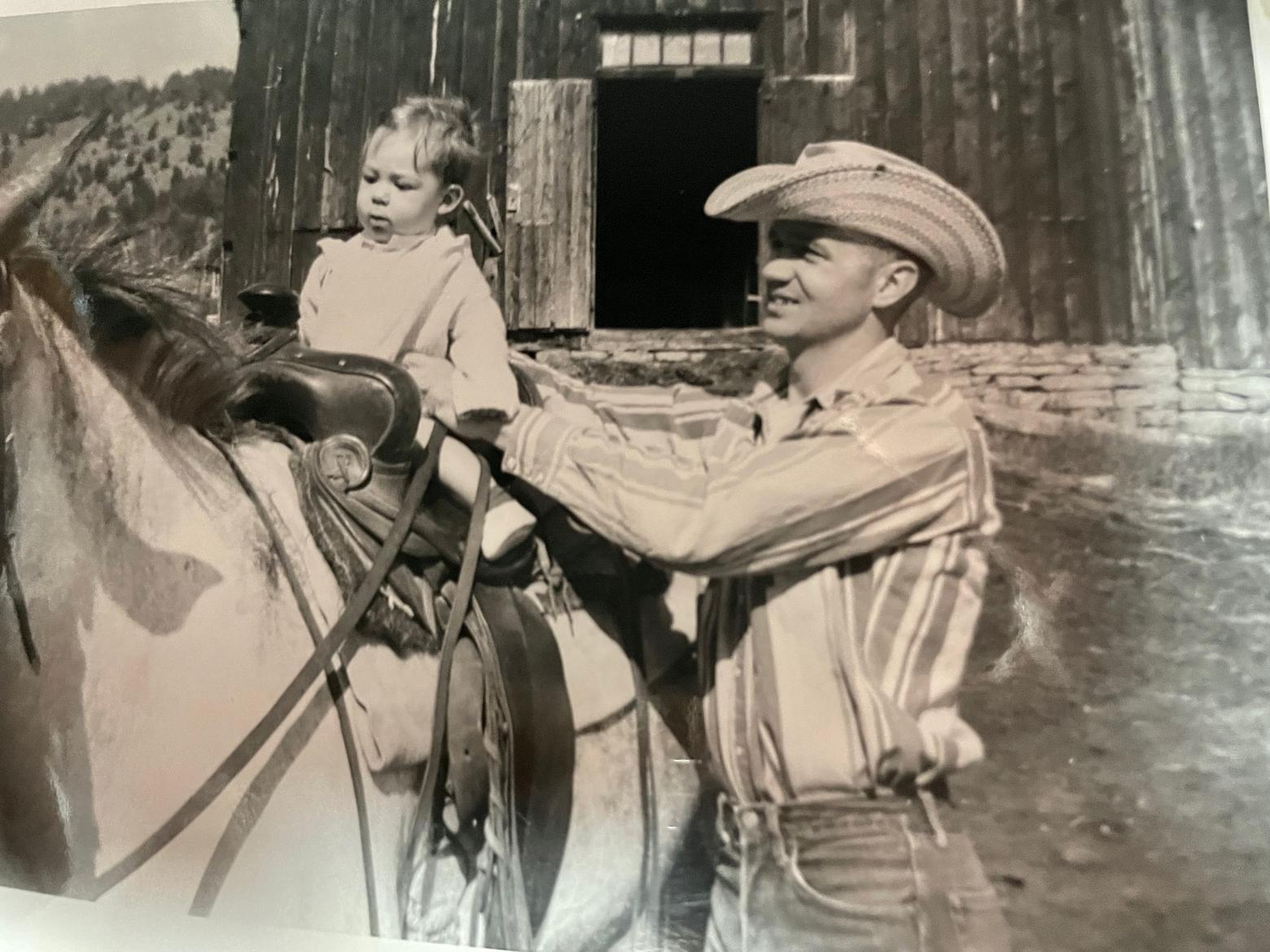 Rowland's father, right, was a school teacher but he knew his way around a horse and helped out rancher friends and neighbors whenever they needed it. Here, he puts his toddler son, Rowland, in the saddle. Photo courtesy Russell Rowland