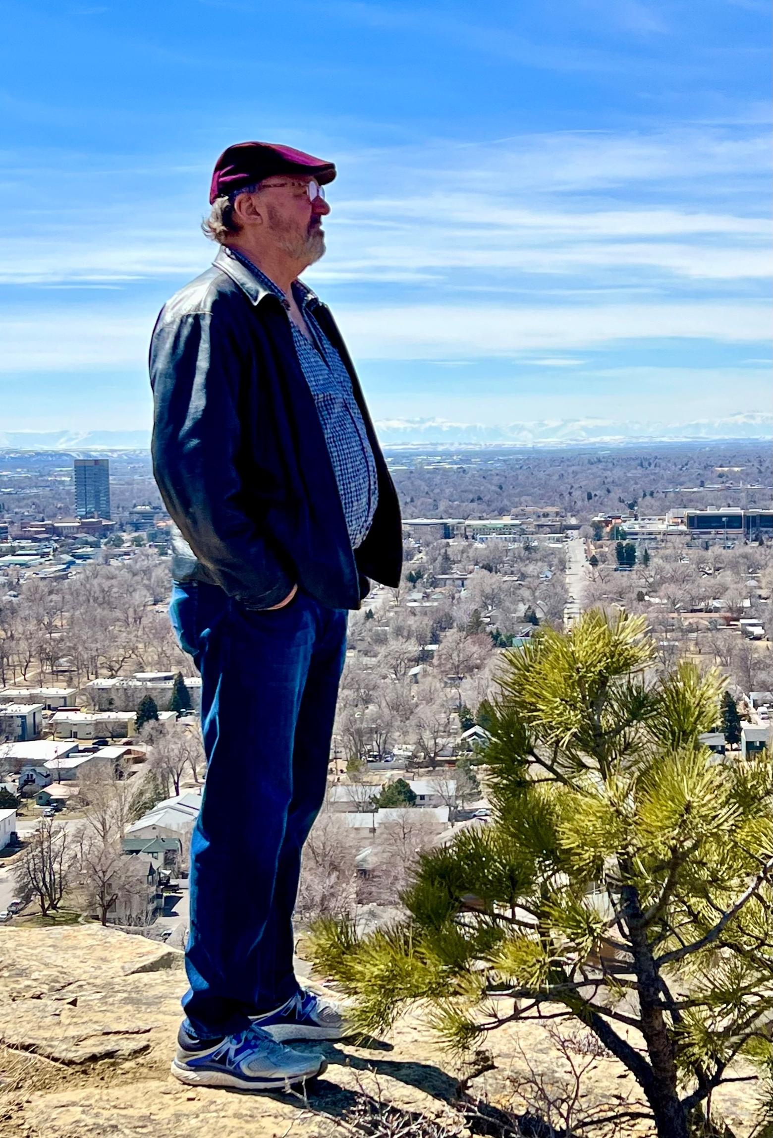Russell Rowland stands on the famous rimrock geological formations above Billings, Montana.  Behind him in the distance are the snow-capped Absaroka-Beartooth mountains and the wild Greater Yellowstone Ecosystem. Rowland and other Billings residents feel a strong connection not only toward the Yellowstone region, but the state's prairies of true big skies, broken eroded landforms and hardscrabble people who need to be tough to persevere. They're a different breed from the funhog culture found in Bozeman and Big Sky. 