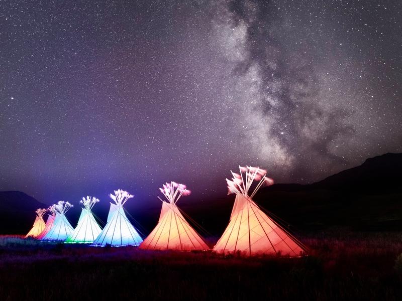 Teepees aglow beneath the Milky Way on Yellowstone's front doorstep