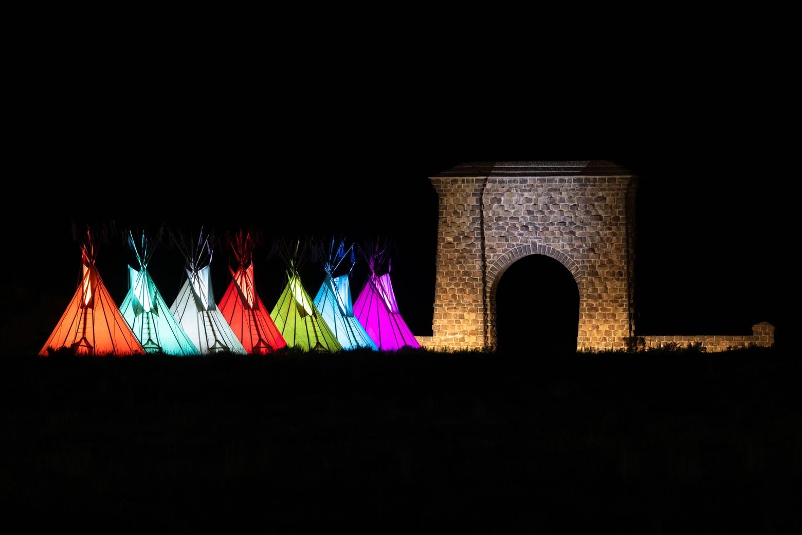 Teepees, colorfully lit, stand next to Roosevelt Arch at the northern entrance to Yellowstone. Photo courtesy Jacob W. Frank/NPS