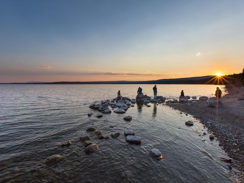 Visitors in Yellowstone National Park contemplate the setting sun on the shores of Yellowstone Lake
